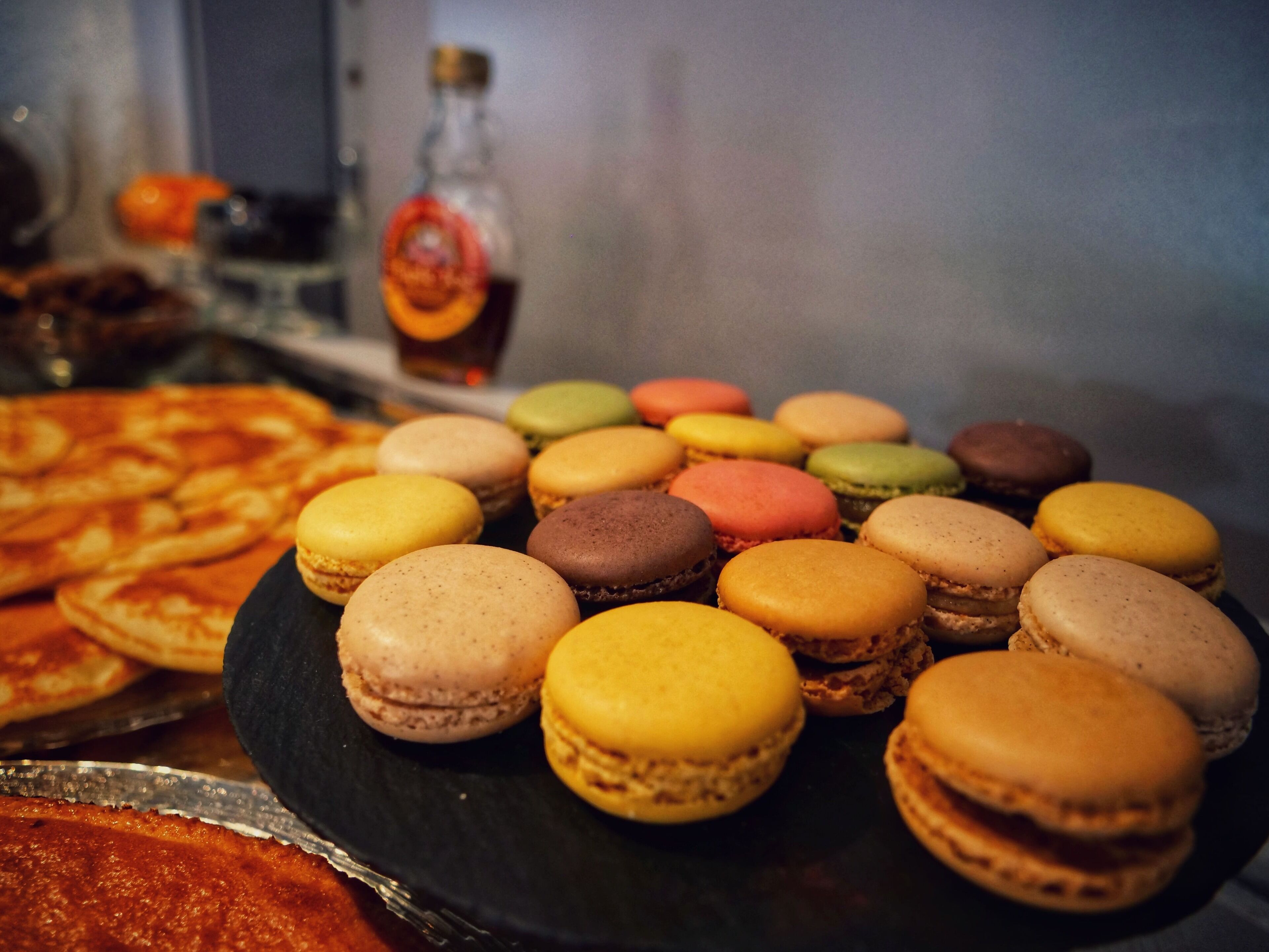 Diverse desserts, waaronder macarons en pizza, op een zwart bord.