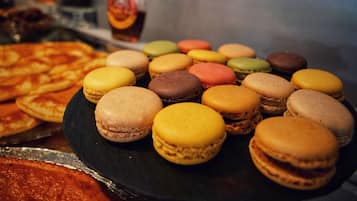 Diverse desserts, waaronder macarons en pizza, op een zwart bord.
