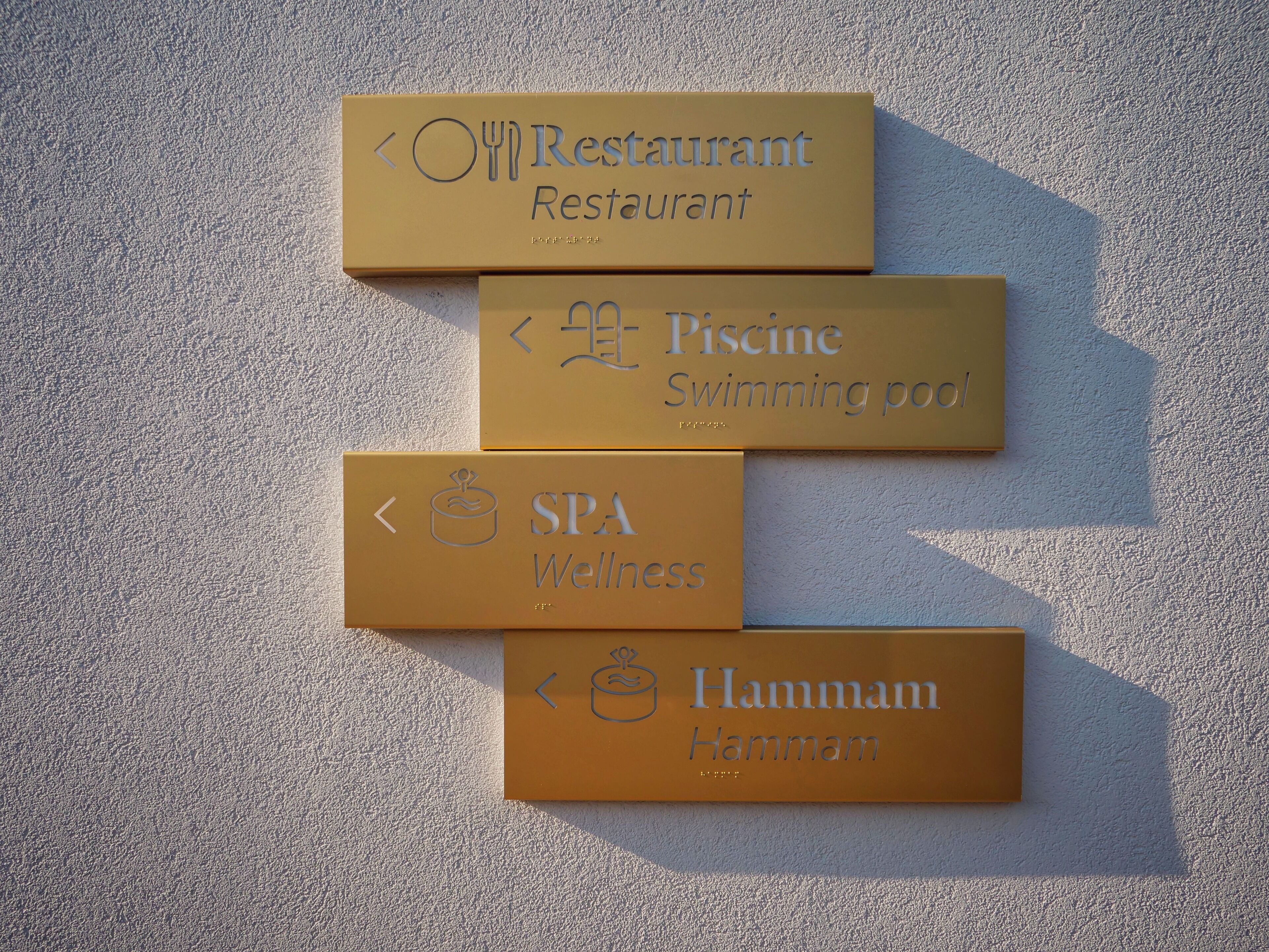 Vier richtingsborden voor een spa, restaurant, zwembad en hammam.