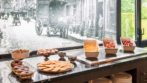 A breakfast buffet with pastries and a vintage street scene backdrop. - Kyriad Dieppe - Saint Aubin Sur Scie (Saint-Aubin-sur-Scie)