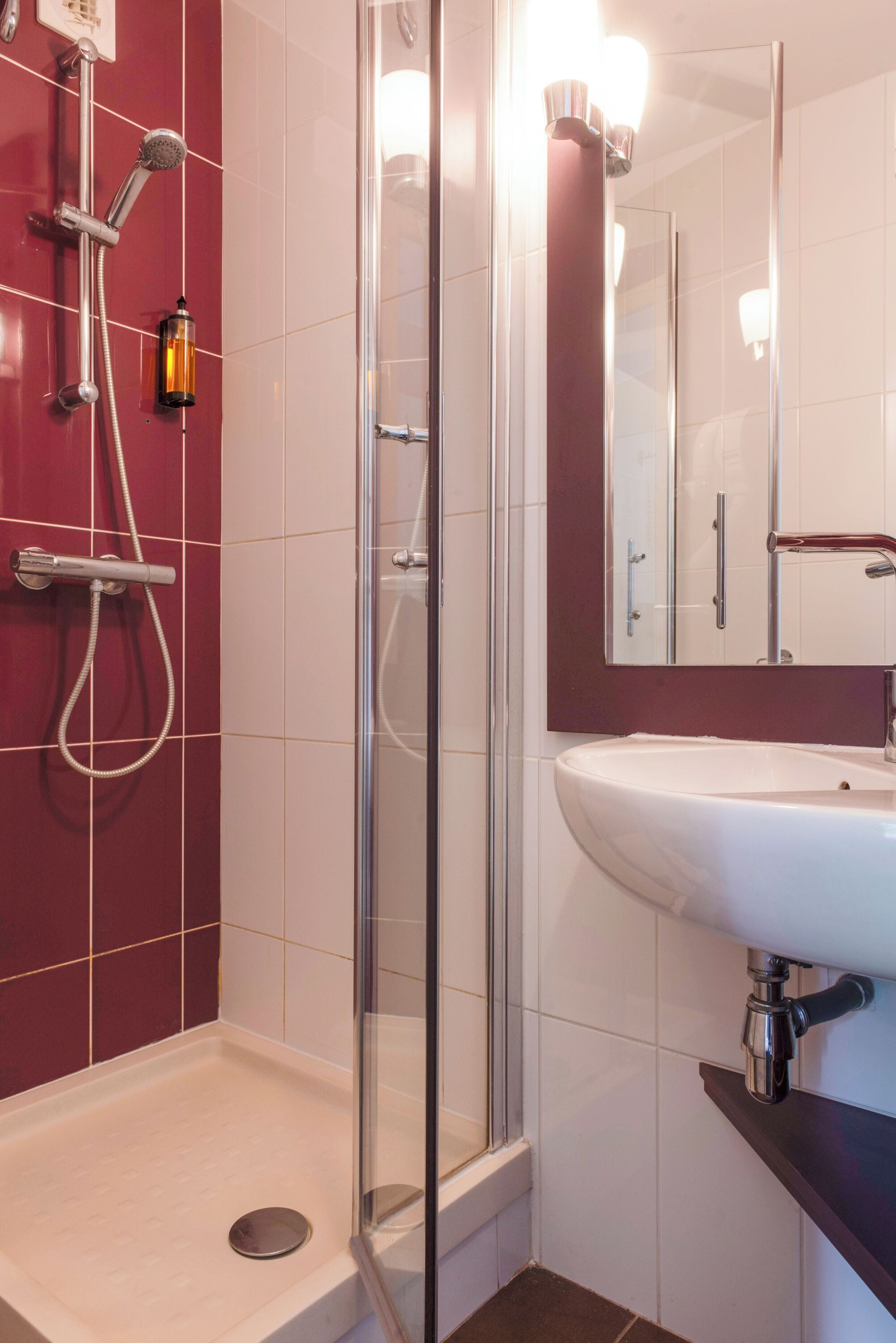 A bathroom with a glass-enclosed shower, a white sink, and a mirror above it.