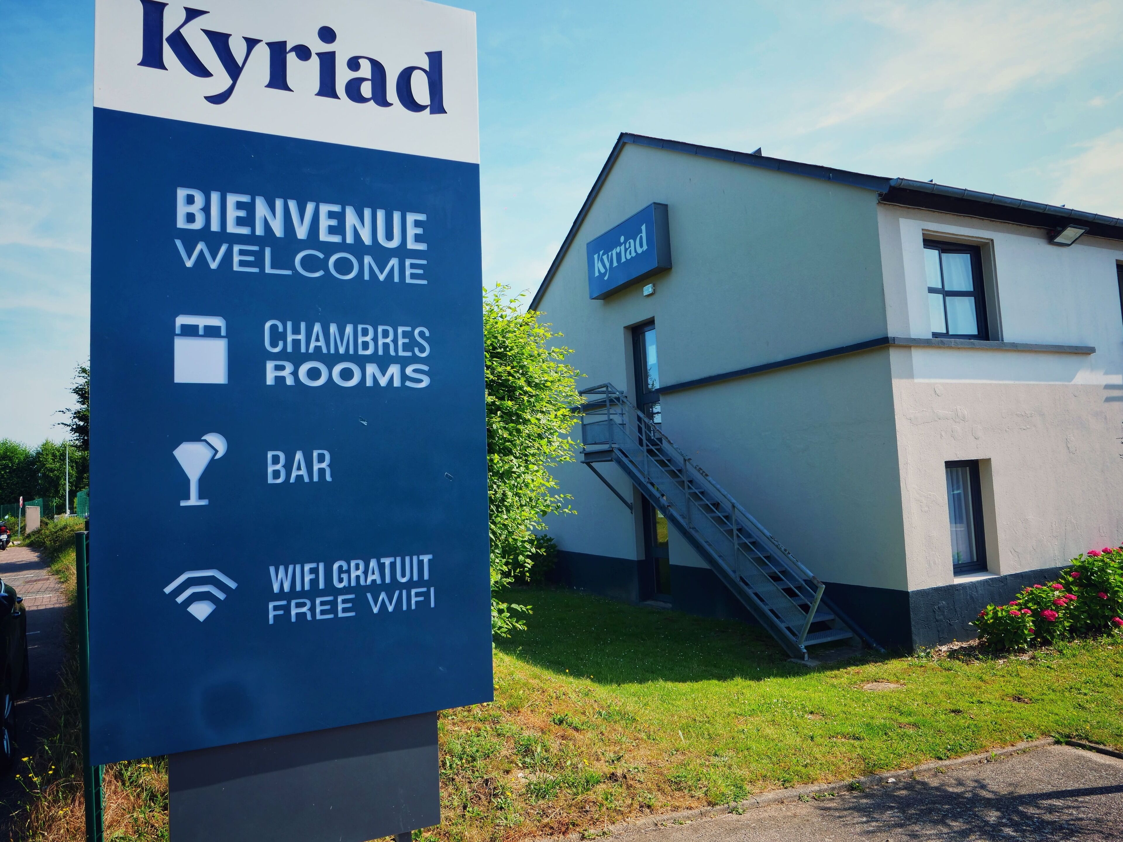 A sign for a hotel named 'Kyriad' with amenities including rooms, a bar, and free WiFi.