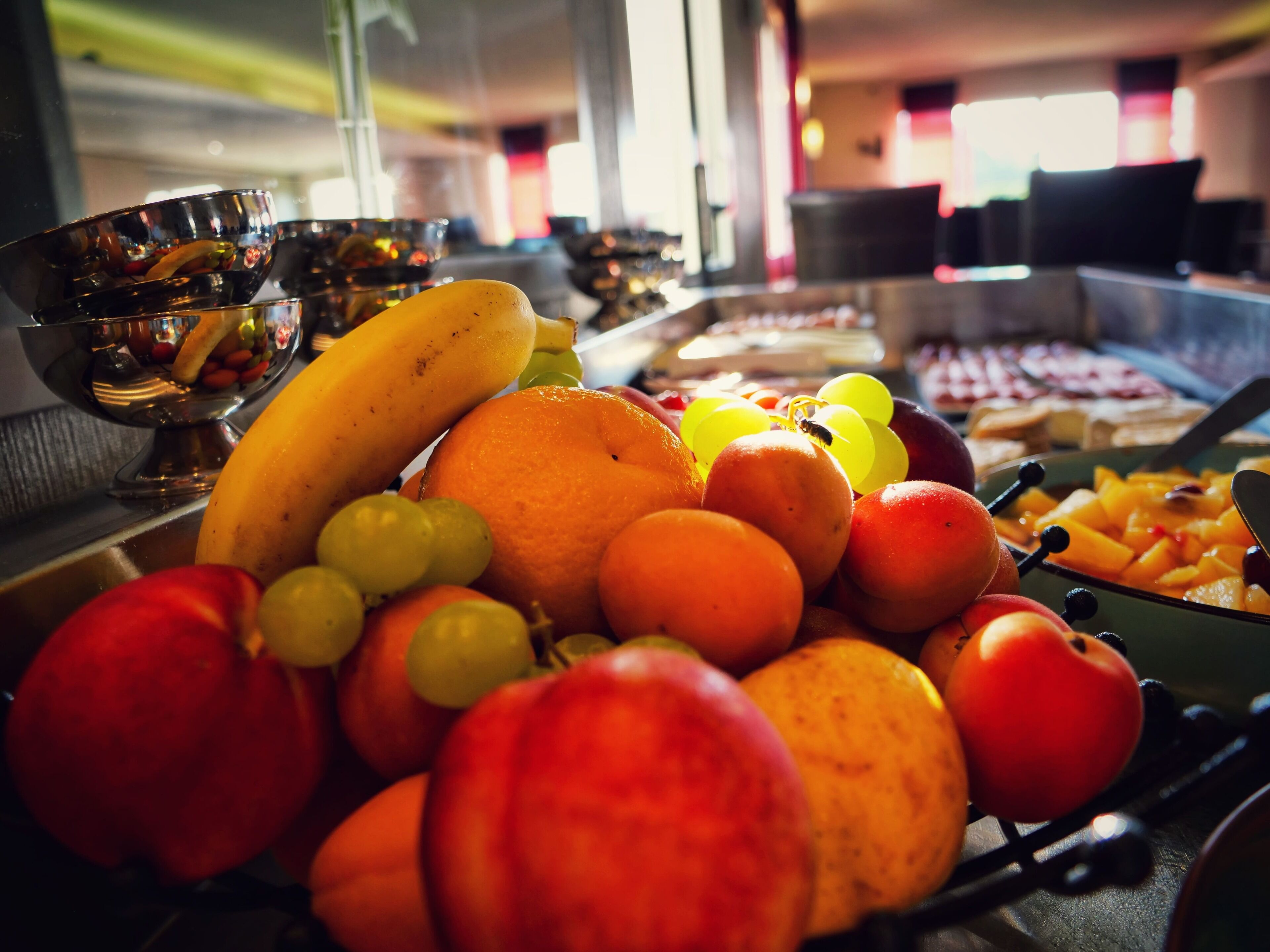 Un bufé con diversas frutas y verduras, incluyendo plátanos, naranjas y tomates.