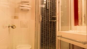 A small bathroom with a shower, toilet, and a sink.