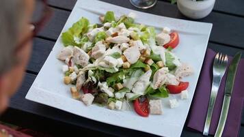 Un piatto di insalata con lattuga, pomodori e crostini su un piatto bianco.