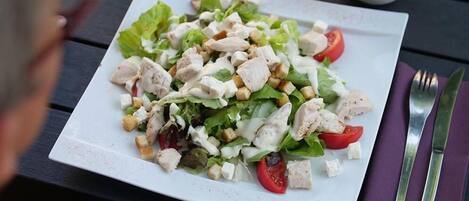 Een bord salade met sla, tomaten en croutons op een wit bord.