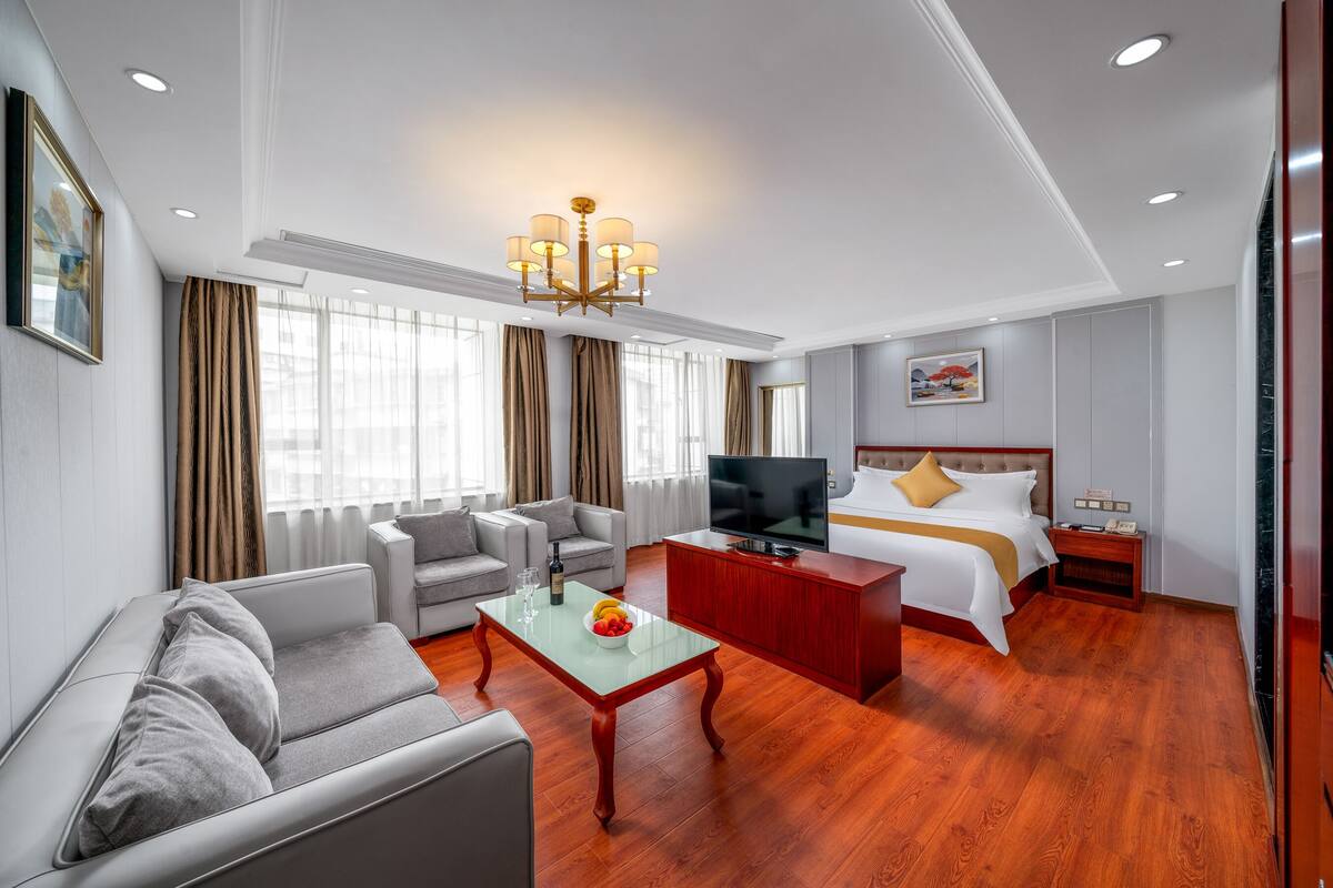 Een hotelkamer met een bank, een televisie, een bed, een houten salontafel en een rode kast.