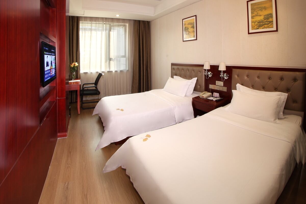A hotel room with two beds, a TV, a desk, and a chair.