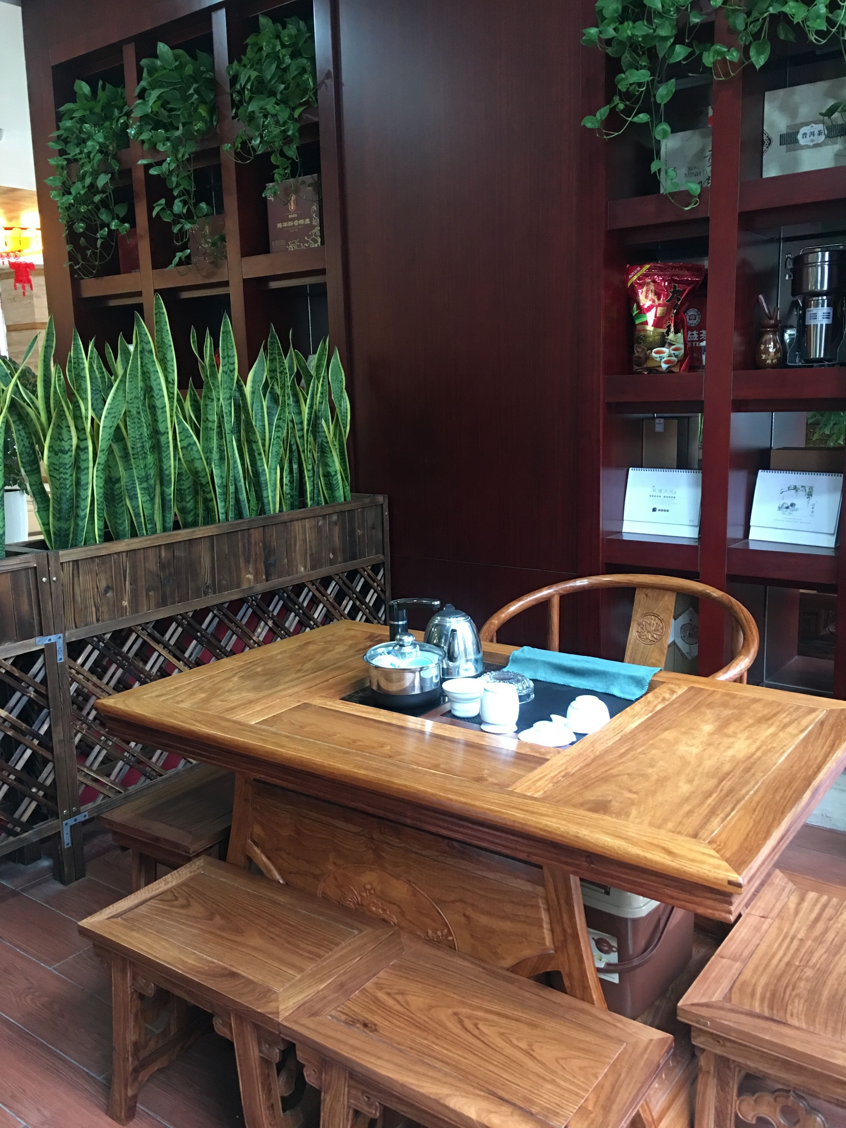 Une table de salle à manger en bois, accompagnée d’un banc, d’une bouilloire, d’une théière, de tasses et d’un plateau.