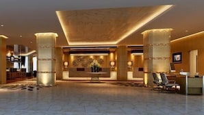 Um hall amplo com balcão de recepção, área de estar e grandes colunas.