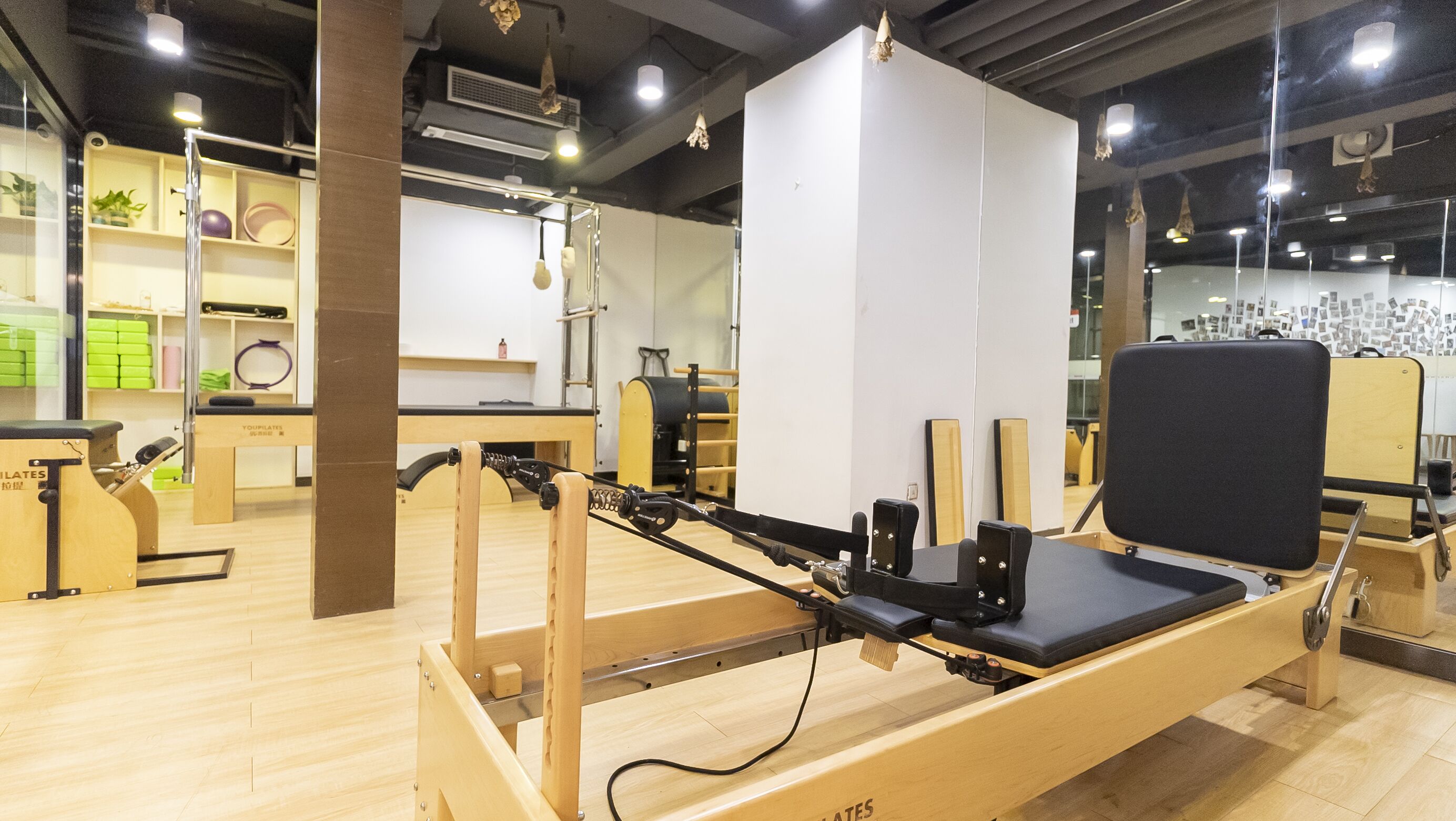 Un estudio de Pilates con equipo de madera, un muro con espejos y suelo de madera.