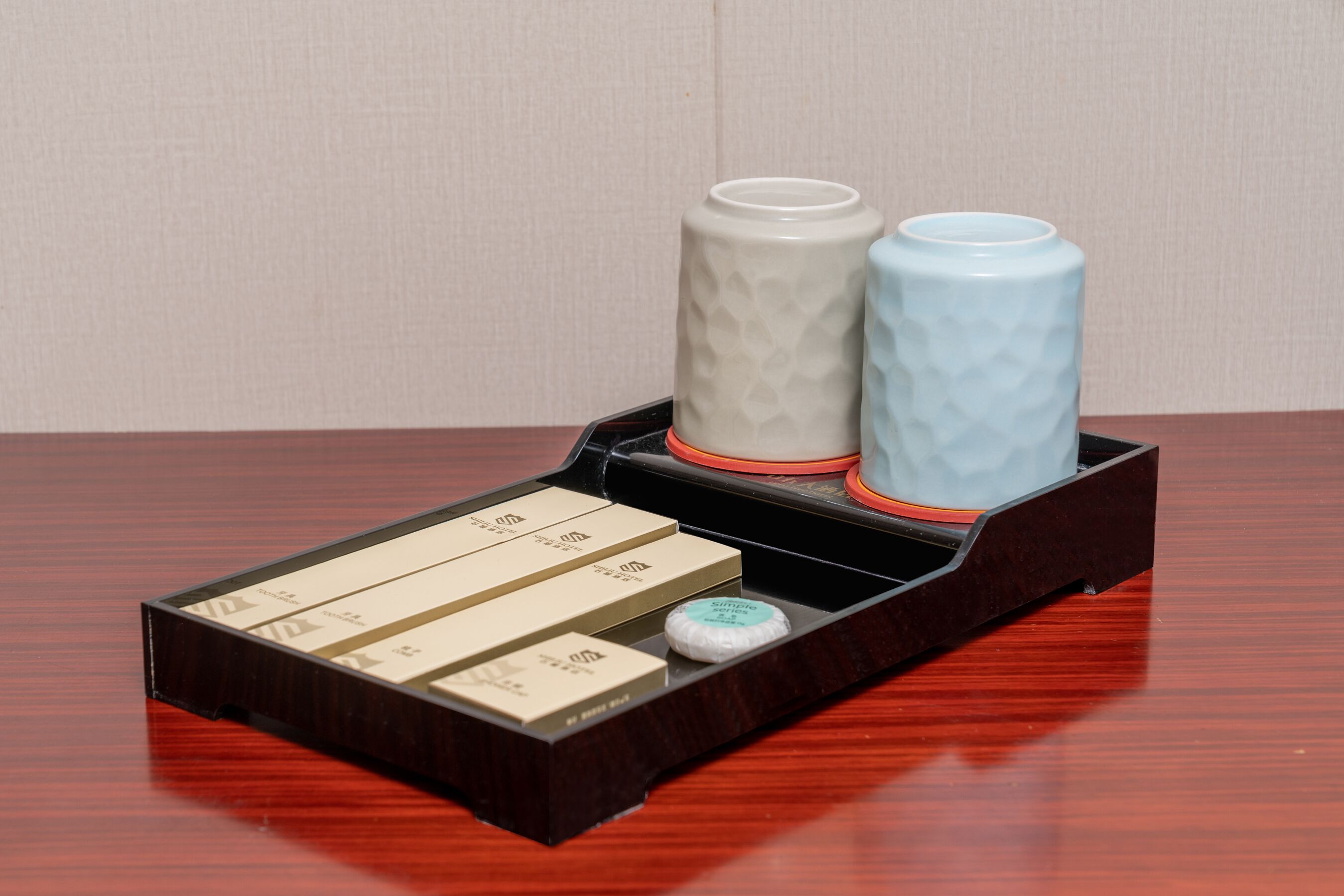 A wooden tray with two ceramic containers and several boxes on a wooden surface.