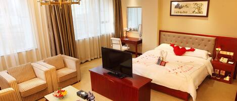 A hotel room with a bed, a television, a desk, a chair, and a coffee table.