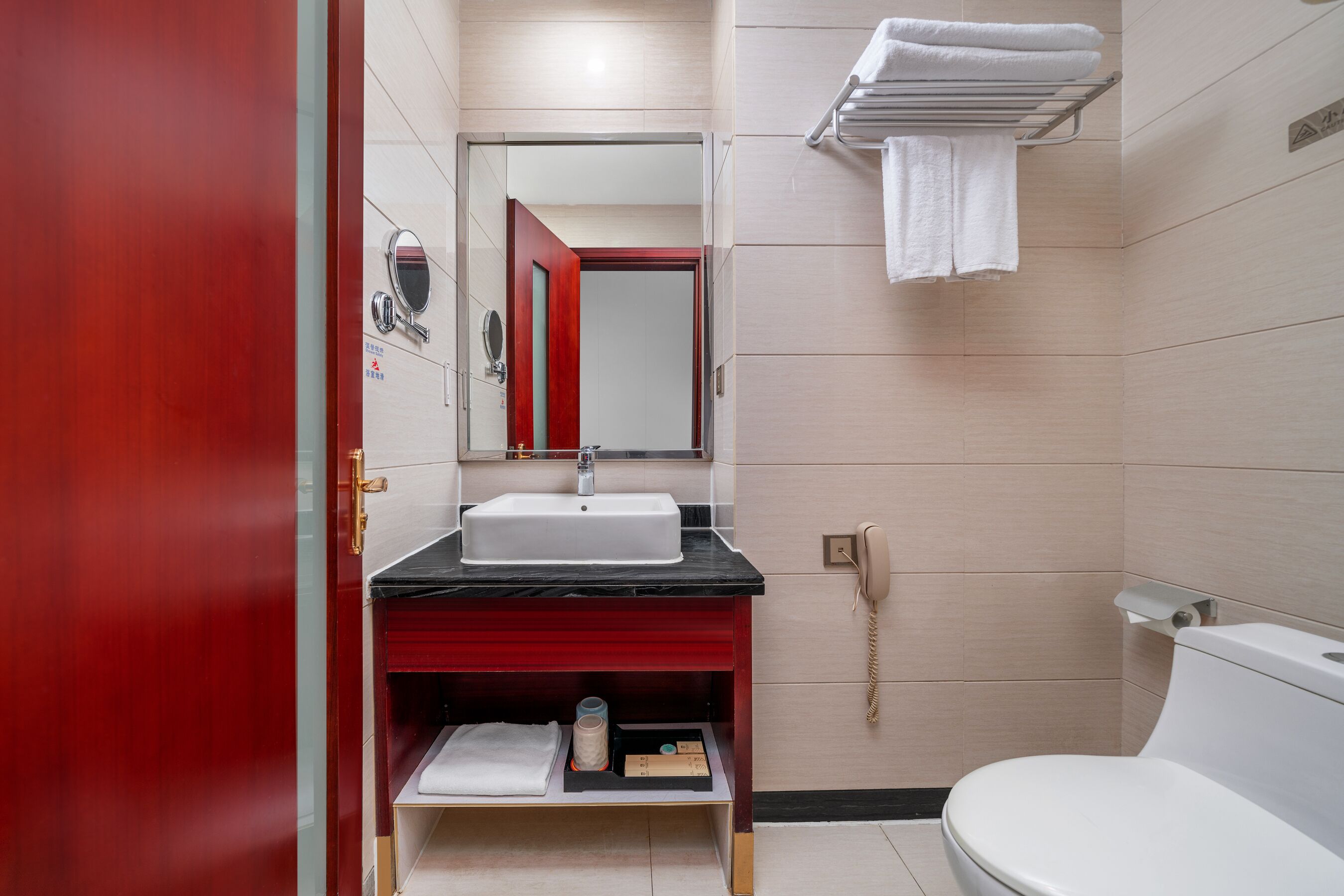 A modern bathroom with a red vanity, a white sink, a mirror, and a toilet.