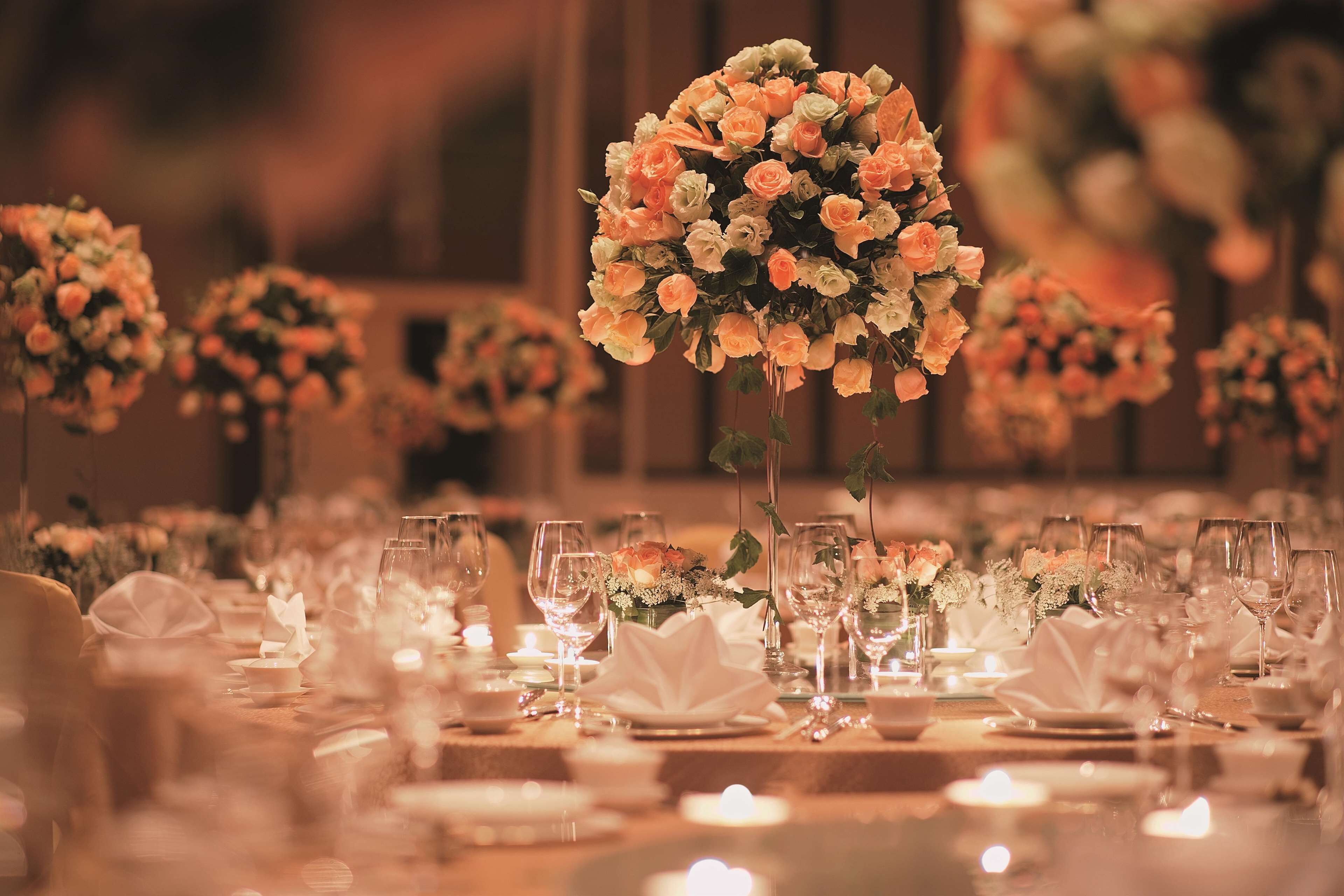 A banquet table set with glassware, plates, and a centerpiece of flowers.