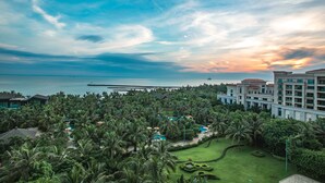 Un resort con piscina, palmeras y vista al océano.