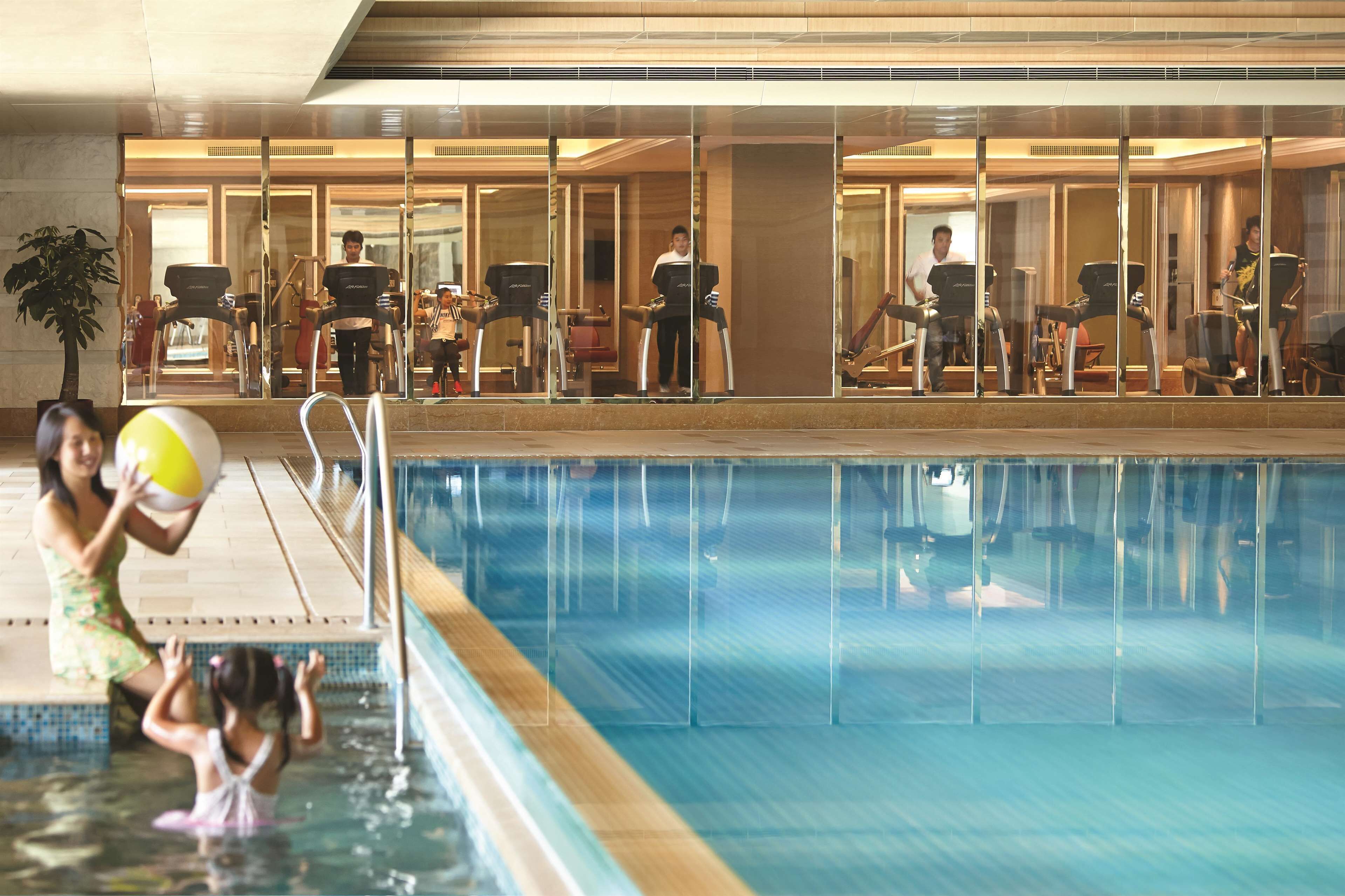 A swimming pool area with exercise equipment and a mirrored wall.