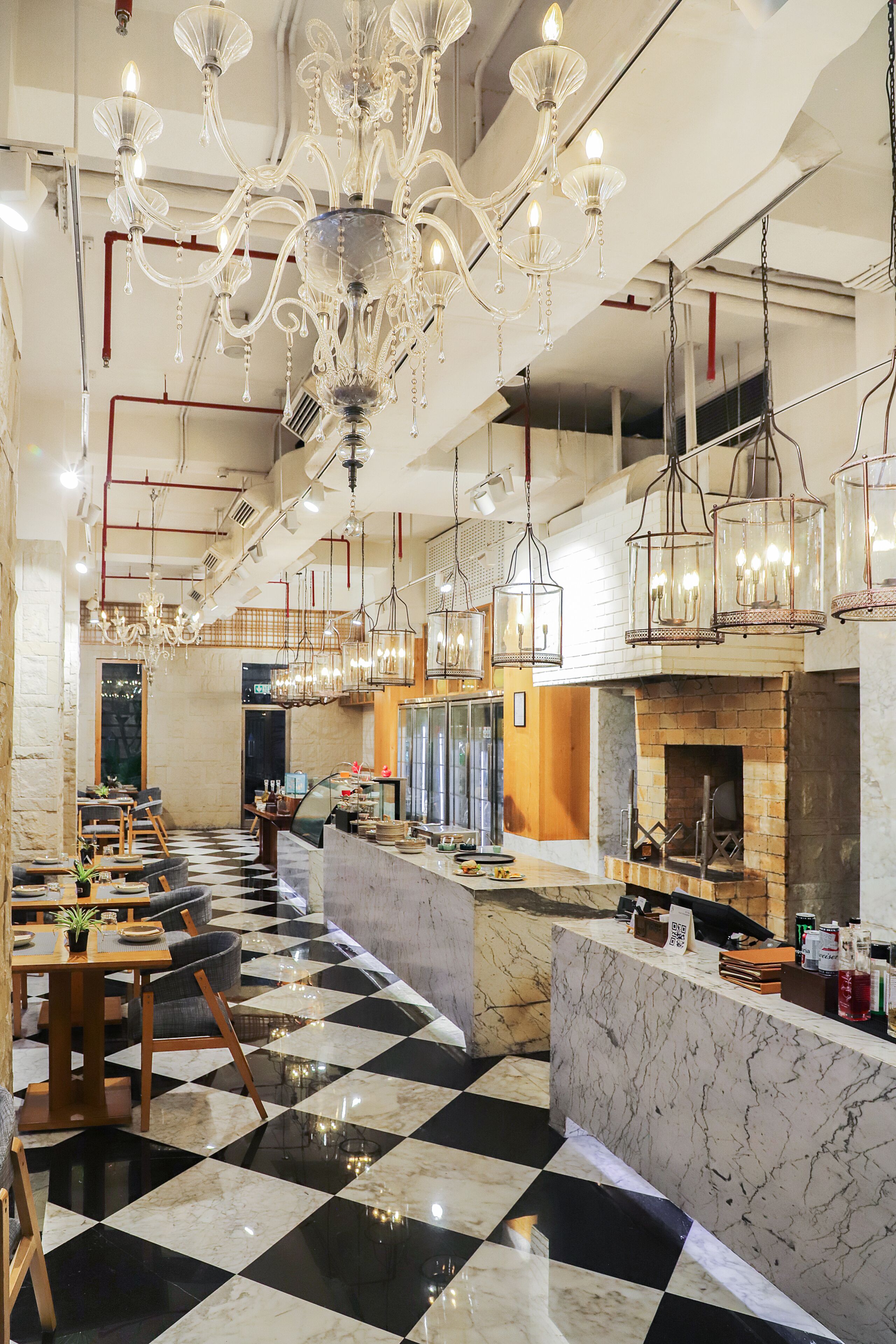A restaurant with a checkered floor, marble counters, and hanging chandeliers.