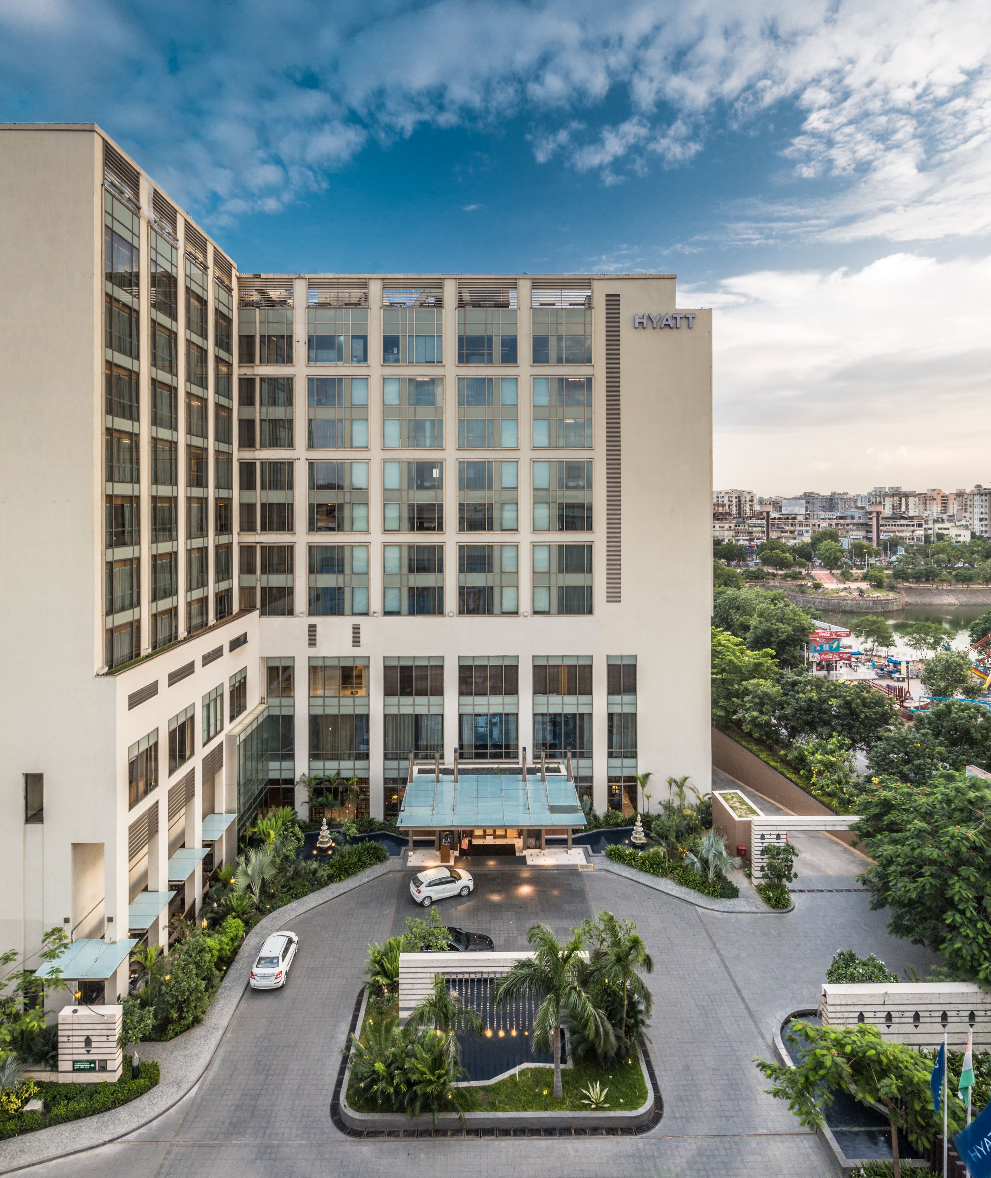 A modern hotel with a large glass facade, a central entrance, and a landscaped courtyard.