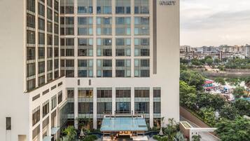 A modern hotel with a large glass facade, a central entrance, and a landscaped courtyard.