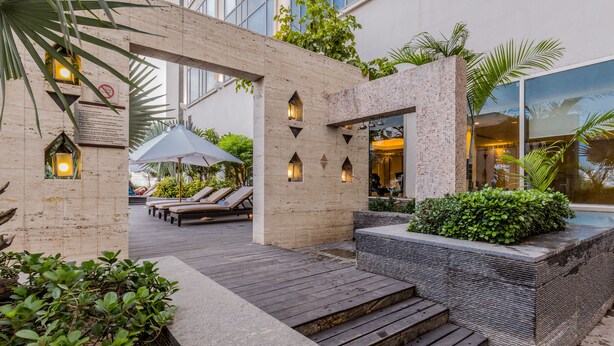 Un espacio exterior moderno con terraza de madera, sillones de descanso y una piscina pequeña.