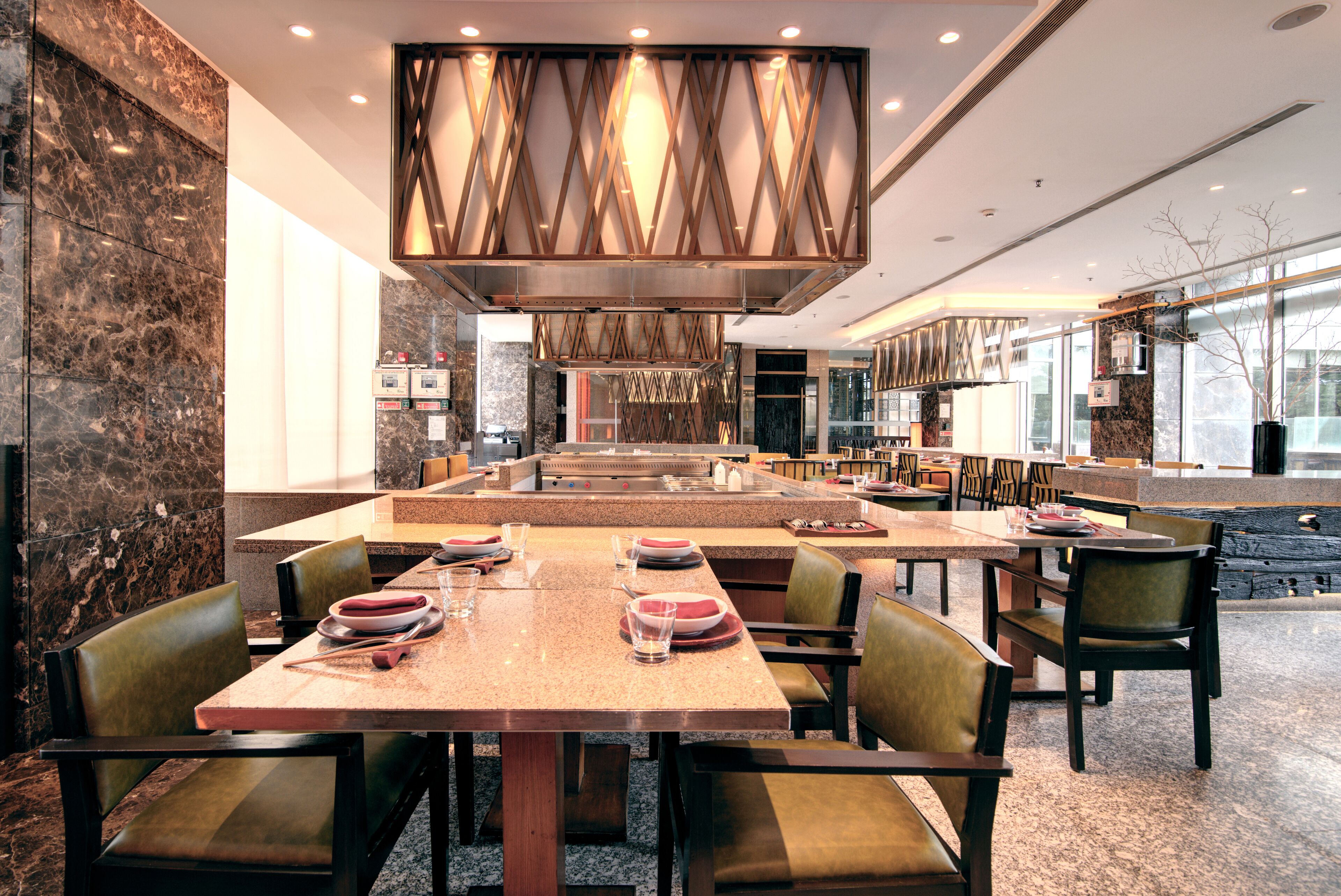 A spacious restaurant with a central island, high ceiling, and modern decor.