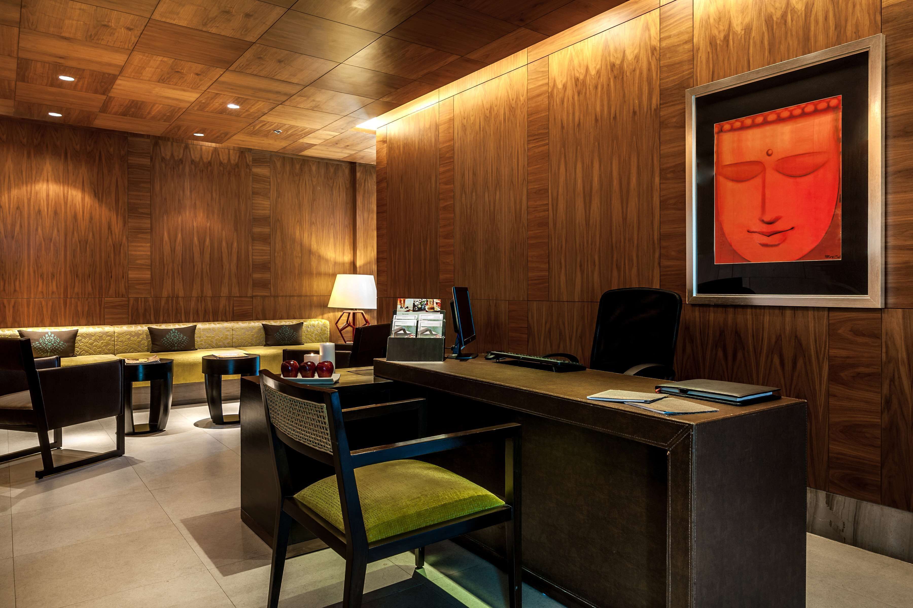 A modern hotel lobby with a wooden interior, a reception desk, a sofa, and a framed artwork on the wall.