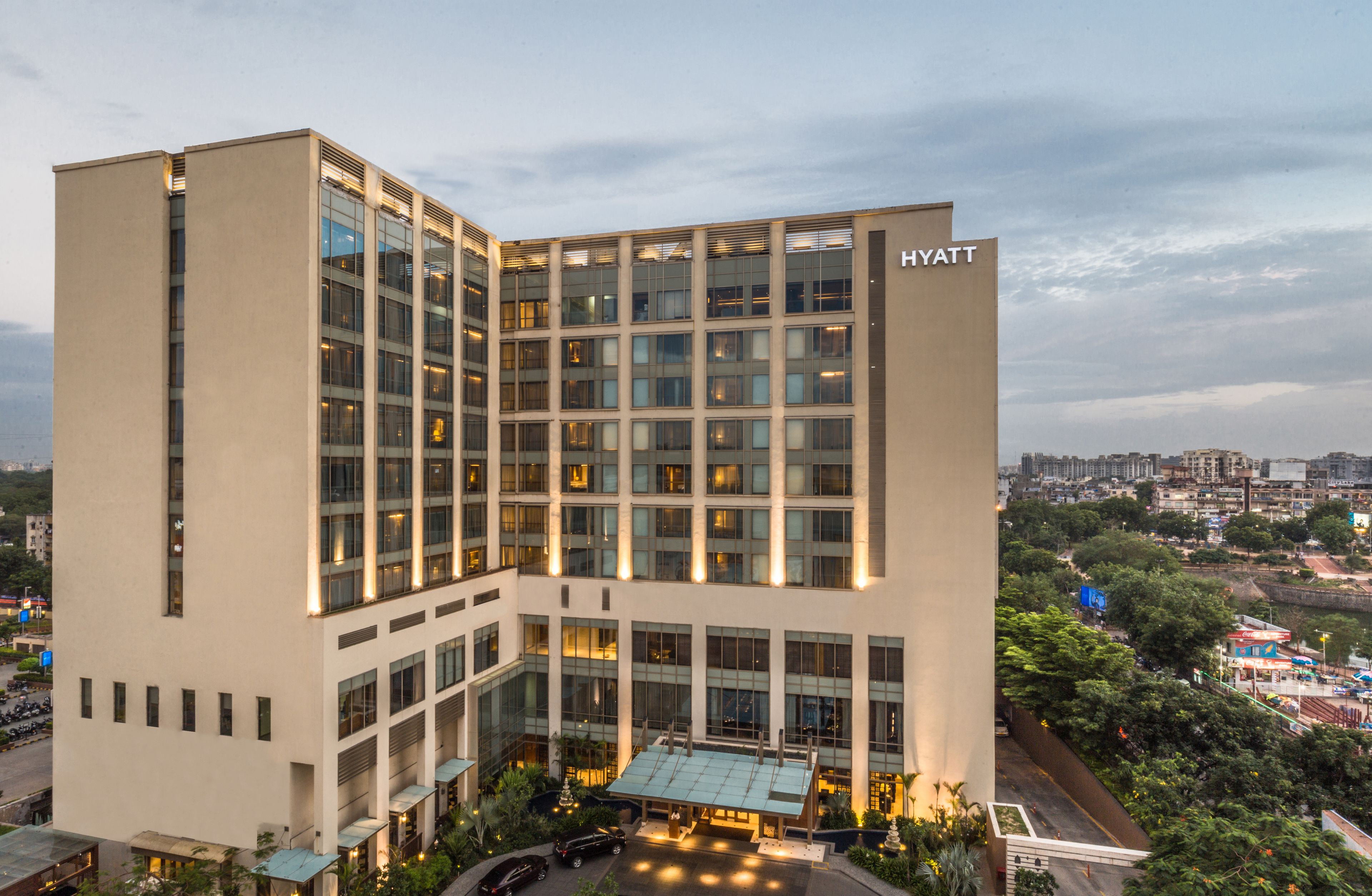 A modern hotel with a glass facade, multiple floors, and a visible "HYATT" sign.