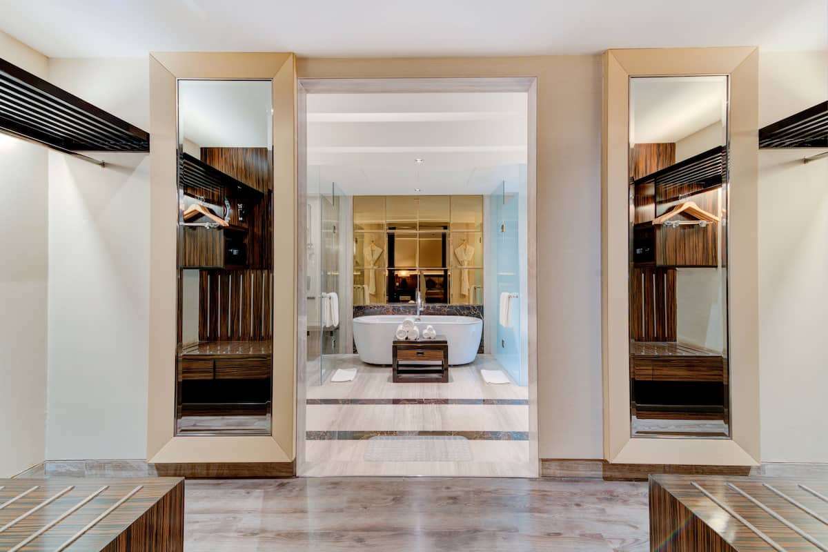 A modern bathroom with a freestanding bathtub, a vanity with a mirror, and a walk-in closet with wooden paneling.