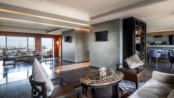 A modern hotel lobby with a seating area, a round table with a vase, and a city view.