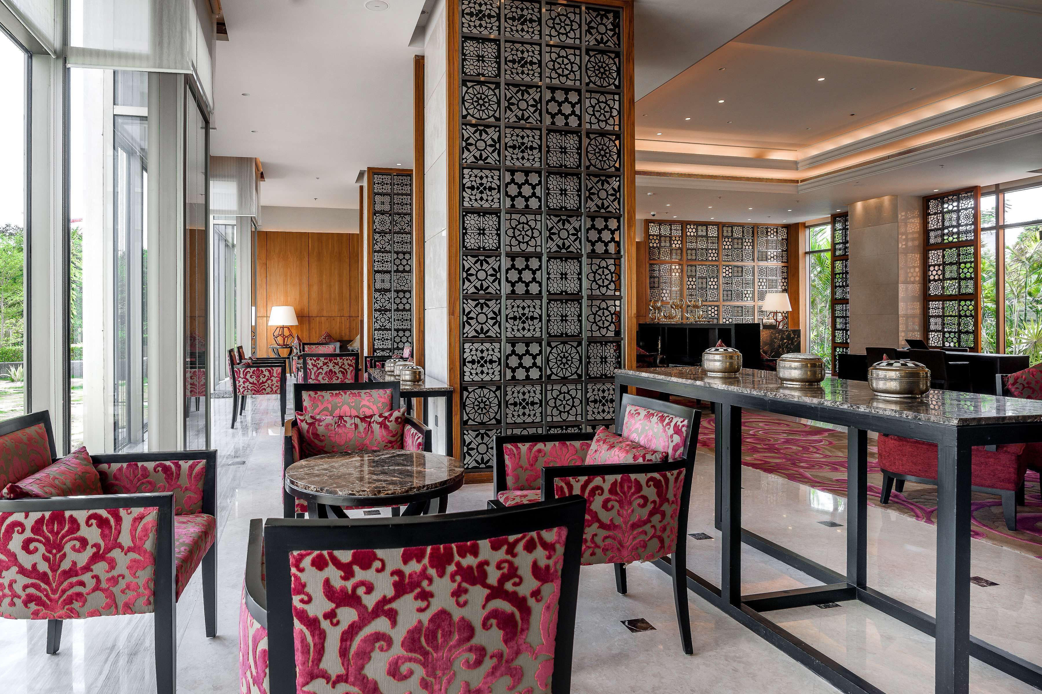 A modern interior with a dining area featuring a glass-top table, patterned chairs, and decorative panels.