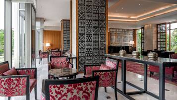 A modern interior with a dining area featuring a glass-top table, patterned chairs, and decorative panels.