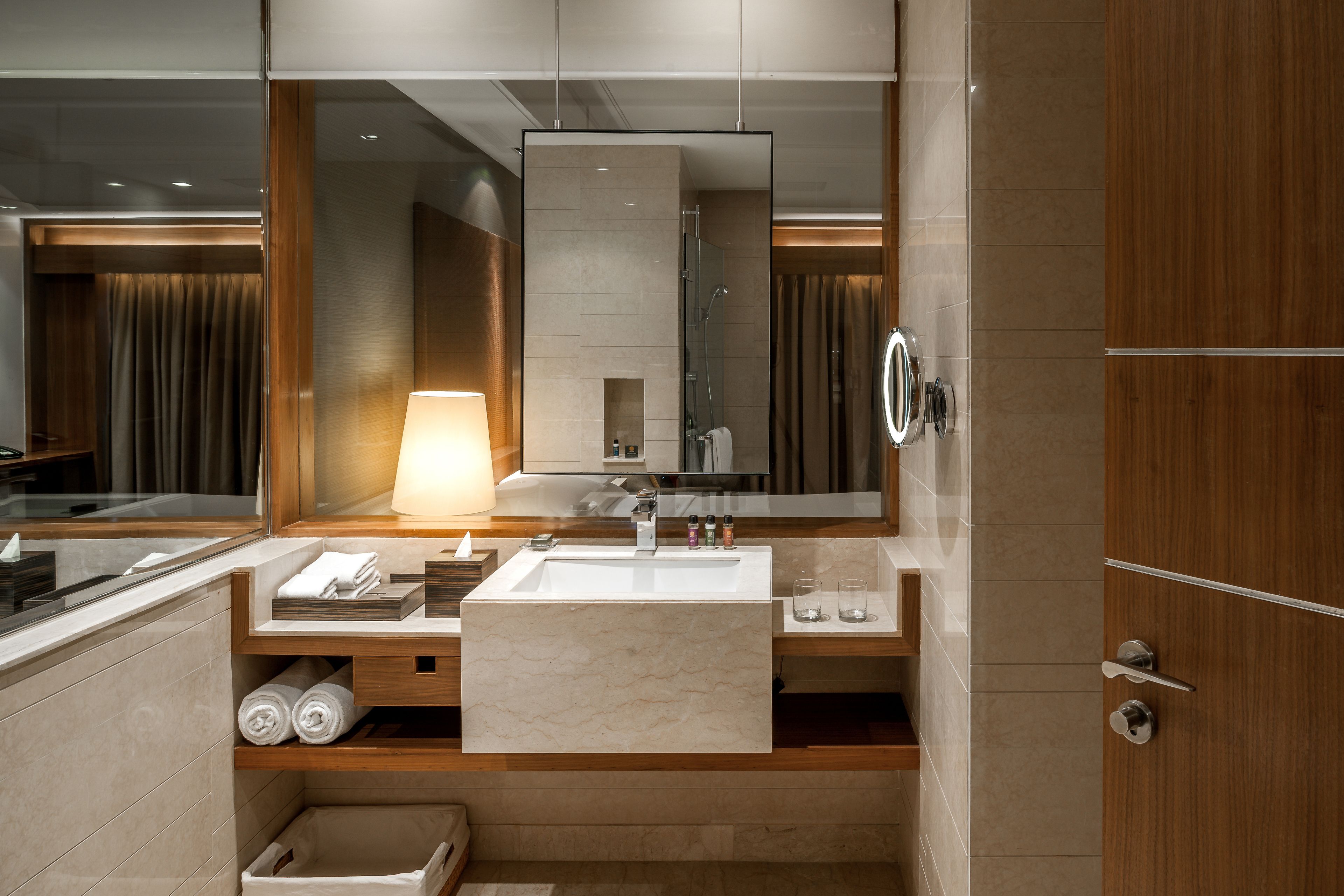 A modern bathroom with a large mirror, a sink, and a shower.