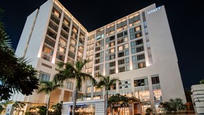 Un hotel moderno con un llamativo letrero de 'HYATT', que presenta un diseño limpio y rectangular con varios pisos y grandes ventanales.