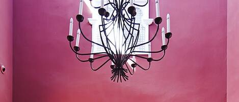 A room with a checkered floor, a dark reception desk, a chandelier, and two wooden planters.
