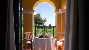 A balcony with a table set for breakfast, chairs, and a view of greenery. - Hotel Isla Canela Golf (Ayamonte)