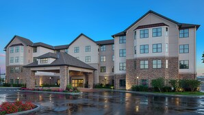 A multi-story hotel with a central entrance, large windows, and a parking lot. - Homewood Suites by Hilton Carle Place - Garden City, NY (Carle Place)