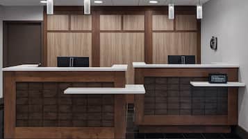 A hotel reception area with two reception desks, wooden paneling, and a sign indicating 'Hilton Honors'.