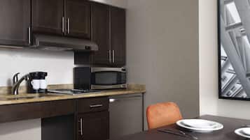 A compact kitchen with dark cabinetry, a microwave, a coffee maker, and a dining area with a table and chairs.