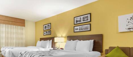 Una habitación de hotel con dos camas individuales, un sofá, una lámpara y cuadros en la pared.