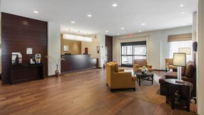Un hall de hotel con una recepción, un área de estar y un ventanal grande.