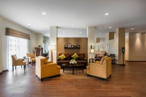 A spacious lobby with a brown sofa set, a coffee table with flowers, and a wall-mounted picture frame. - Sleep Inn & Suites Fargo Medical Center (Fargo)