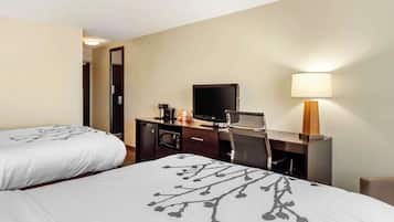 A hotel room with two beds, a desk with a computer, a coffee maker, and a lamp.