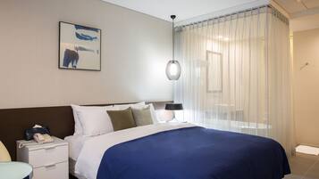 A hotel room with a large bed, a bedside table with a phone, a lamp, and a painting on the wall.