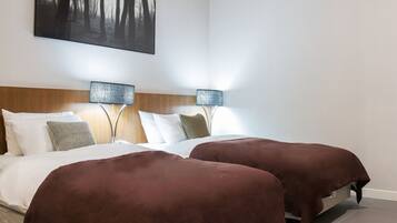 Una habitación de hotel moderna con una cama grande, dos mesitas de noche, un cabecero y una obra de arte colgada en la pared.