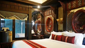 Un grand lit avec une literie rouge et blanche, une tête de lit en bois et un miroir.