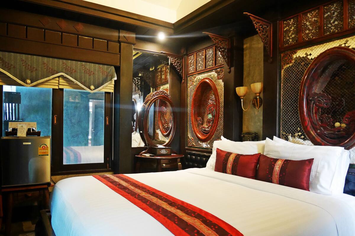 Un grand lit avec une literie rouge et blanche, une tête de lit en bois et un miroir.