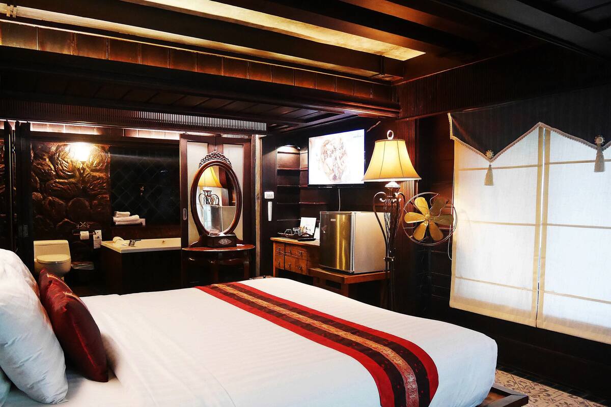 Une chambre d’hôtel équipée d’un lit, d’un bureau, d’un miroir, d’une lampe et d’un téléviseur.
