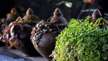 Una hilera de macetas rústicas cubiertas de musgo, con formas cónicas, probablemente parte de un jardín o decoración exterior.