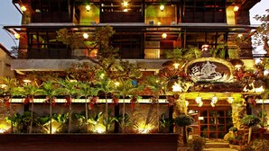 Un immeuble à plusieurs étages doté de balcons, d’un éclairage extérieur et d’une grande variété de plantes.